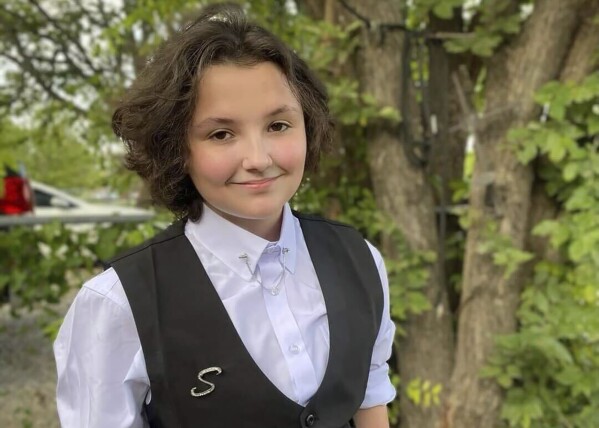 In this image provided Malia Pila, Nex Benedict poses outside the family's home in Owasso, Okla., in December 2023. A recently released police search warrant reveals more details in the case of Nex Benedict, a nonbinary Oklahoma student who died a day after a high school bathroom fight that may have been prompted by bullying over gender identity. (Sue Benedict via AP)