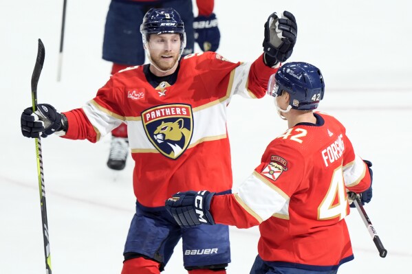 Florida Panthers center Sam Bennett (9) congratulates defenseman Gustav Forsling (42) after Forsling scored the game-winning goal during an overtime period of an NHL hockey game against the Washington Capitals, Saturday, Feb. 24, 2024, in Sunrise, Fla. (AP Photo/Wilfredo Lee)