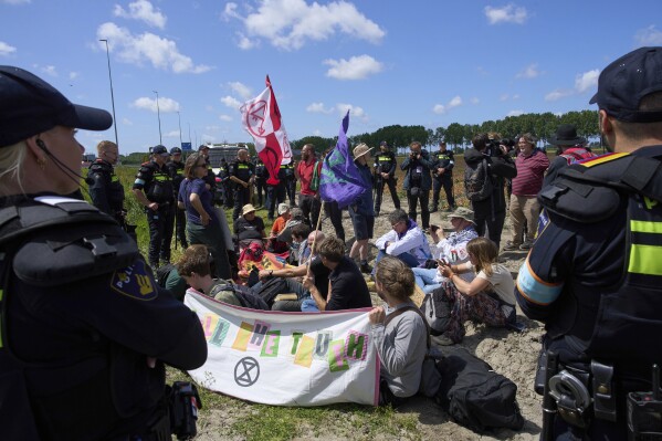 Police detain demonstrators with Extinction Rebellion who attempted to block the A44 motorway, closed off to all traffic except for arriving and departing world leaders, in Abbenes, Netherlands, Monday, June 23, 2025, for the NATO summit in The Hague. (AP Photo/Peter Dejong)