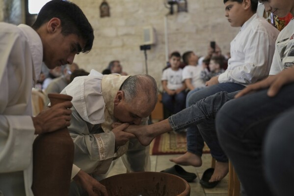 Rev. Tony Chalhoub, center, of the Maronite Church of St. George kisses a foot during the Washing of the Feet ceremony in Quraye, near the southern port city of Sidon, Lebanon, Thursday, April 17, 2025. (AP Photo/Hassan Ammar)