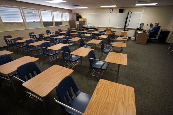 FILE - Math teacher Doug Walters sits among empty desks as he takes part in a video conference with other teachers to prepare for at-home learning at Twentynine Palms Junior High School in Twentynine Palms, Calif., Aug. 18, 2020. A new study finds that students around the world suffered historic setbacks in reading during the pandemic and even deeper losses in math, with test score decreases so wide that the United States climbed in global rankings simply by falling behind less sharply. (AP Photo/Gregory Bull, File)