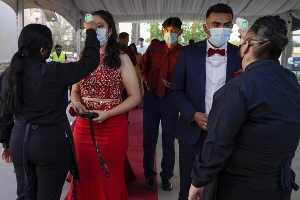 Grace Gardens Event Center employees check temperatures of young people attending prom at the Grace Gardens Event Center in El Paso, Texas on Friday, May 7, 2021. Around 2,000 attended the outdoor event at the private venue after local school districts announced they would not host proms this year. Tickets cost $45. (AP Photo/Paul Ratje)