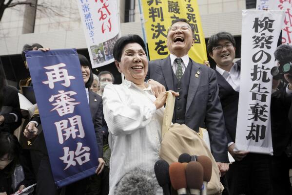 Hideko Hakamada, center left, sister of Iwao Hakamada, celebrates following a court decision at Tokyo Hight Court in Tokyo Monday, March 13, 2023. Tokyo’s high court on Monday ordered a retrial for the 87-year-old former boxer who has been on death row for nearly six decades after his murder conviction that his lawyers said was based on forced confession and fabricated evidence. A banner, left, reads " Retrial starts." (Kyodo News via AP)