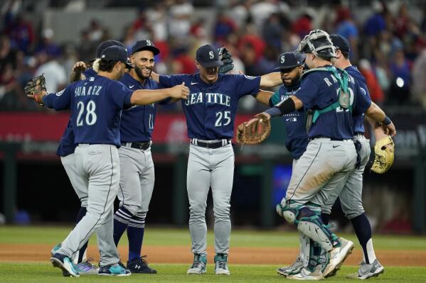 Seattle Mariners' Eugenio Suarez (28), Dylan Moore (25), Cal Raleigh, right, and others celebrate their 3-2 win against the Texas Rangers in a baseball game, Saturday, July 16, 2022, in Arlington, Texas. (AP Photo/Tony Gutierrez)
