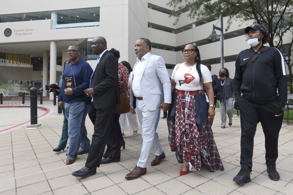 FILE - Attorney Ben Crump, second from left, walks with Ron Lacks, left, Alfred Lacks Carter, third from left, both grandsons of Henrietta Lacks, and other descendants of Lacks, outside the federal courthouse in Baltimore, Oct. 4, 2021. The family of Henrietta Lacks is settling a lawsuit against a biotechnology company it accuses of improperly profiting from her cells. Their federal lawsuit in Baltimore claimed Thermo Fisher Scientific has made billions from tissue taken without the Black woman’s consent from her cervical cancer tumor. (AP Photo/Steve Ruark, file)
