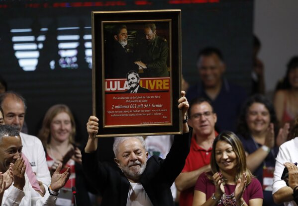 Former Brazilian President Luiz Inacio Lula da Silva holds up a picture that shows him and Cuba's late leader Fidel Castro, during the Workers' Party 7th Congress, in Sao Paulo, Brazil, Friday, Nov. 22, 2019. Da Silva is the unquestioned star of the PT 3-day party convention. Many still think he could be the party's standard-bearer once again in 2022 - when he'll be a 77-year-old cancer survivor who is now barred from seeking office due to a corruption conviction. (AP Photo/Nelson Antoine)