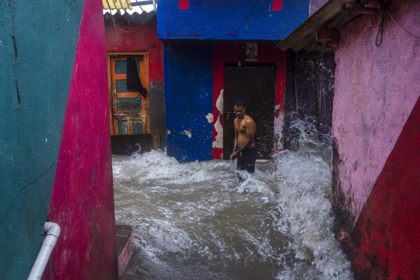 A man watches waves caused by high tide hit his house on the shore of the Arabian Sea in Mumbai, India, Thursday, July 6, 2023. (AP Photo/Rafiq Maqbool)
