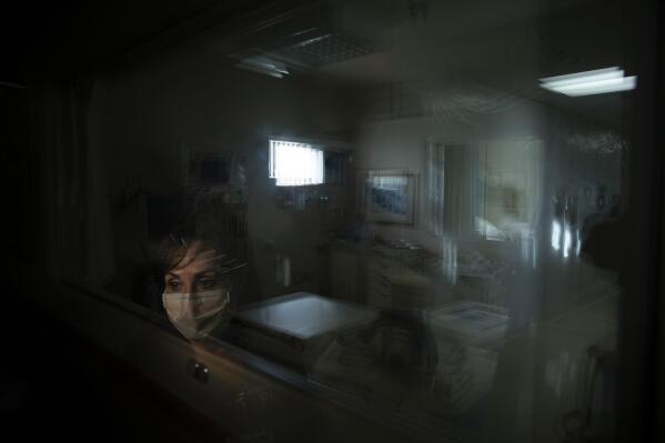 In this photo created with an in-camera multiple exposure, registered nurse Cathy Cullen, part of the first group of nurses who had been treating coronavirus patients in an intensive care unit, stands for a photo in the empty COVID-19 ICU at Providence Mission Hospital in Mission Viejo, Calif., Tuesday, April 6, 2021. Cullen sometimes tears up when thinking about what she and the other nurses endured. "The birth of my children and marriage aside, being a part of this team, this endeavor, and this pandemic is by far the greatest, worst, most rewarding, most painful thing I have ever done in my life," she says. (AP Photo/Jae C. Hong)