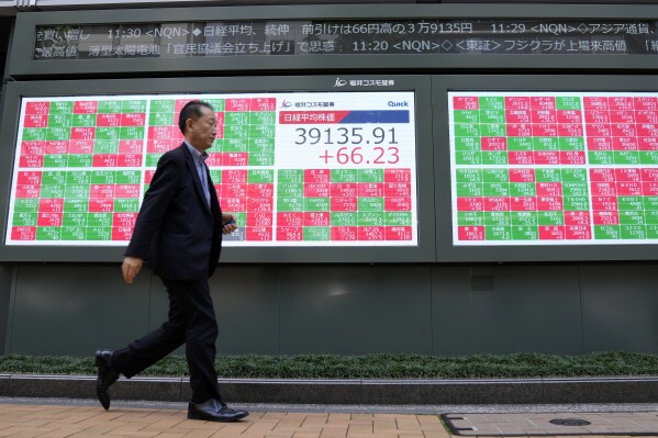 A person walks past an electronic stock board showing Japan's Nikkei 225 index, center, at a securities firm Tuesday, May 21, 2024 in Tokyo. Asian shares mostly fell Tuesday, even as most U.S. stock indexes finished higher, especially technology issues like Nvidia. (AP Photo/Shuji Kajiyama)