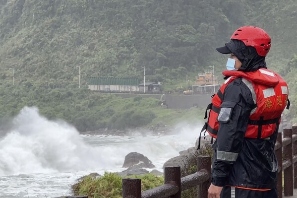 A coast guard officer watches as waves crash on the shore ahead of typhoon Khanun in the port city of Keelung near Taipei in northern Taiwan on Thursday, Aug. 3, 2023. (AP Photo/Johnson Lai)
