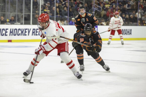 FILE - Boston University's Macklin Celebrini (71) skates with the puck in front of Rochester's Elijah Gonsalves (16) during an NCAA men's college hockey tournament regional game March 28, 2024, in Sioux Falls, S.D. Celebrini has a pretty good idea his NHL future lies with the San Jose Sharks, who hold the first pick in the draft. For now, the 17-year-old center coming off a celebrated freshman season at Boston University isn’t in a rush to get there, yet. (AP Photo/Josh Jurgens, File)