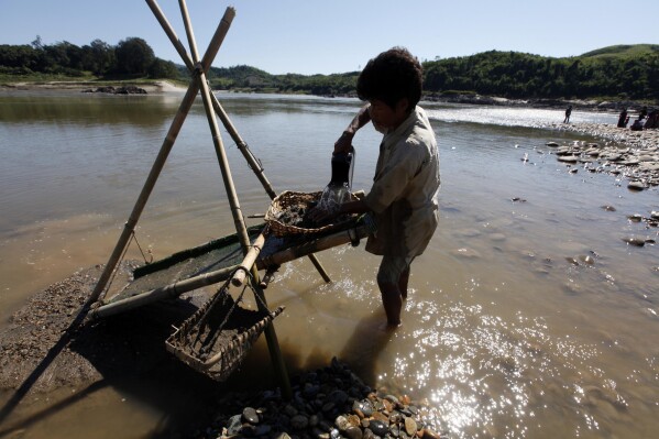 FILE - Myanmar's ethnic Kachin man pans for gold in Myitsone in Myitkyina, Kachin State, about 1,600 kilometers (1,000 miles) north of Yangon, Myanmar, Wednesday Nov. 6, 2013. Myanmar's military government appears to be reviving consideration of a massive China-backed hydroelectric dam project, work on which was suspended more than a decade ago after protests over its possible impact on the environment. (AP Photo/Khin Maung Win, File)