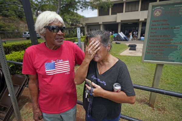 Myrna and Abraham Ah Hee react as they stand in front of an evacuation center at the War Memorial Gymnasium, Thursday, Aug. 10, 2023, in Wailuku, Hawaii. The Ah Hees were there because they were looking for Abraham's brother. Their own home in Lahaina was spared, but the homes of many of their relatives were destroyed by wildfires. They haven't been able to get in touch with Abraham's brother. (AP Photo/Rick Bowmer)