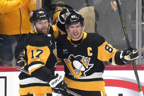Pittsburgh Penguins' Sidney Crosby (87) celebrates his goal with Bryan Rust after scoring during the first period of an NHL hockey game against the Philadelphia Flyers in Pittsburgh, Sunday, Feb. 25, 2024. (AP Photo/Gene J. Puskar)