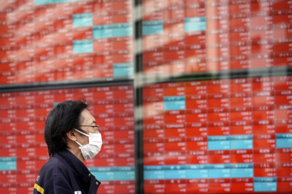 FILE - A post office worker stands in front of an electronic stock board showing Japan's Nikkei 225 index at a securities firm in Tokyo, on Nov. 6, 2023. Asian shares surged higher on Wednesday, Nov. 15 cheered by a rally on Wall Street that was one of the best days of the year following a surprisingly encouraging report on inflation. (AP Photo/Eugene Hoshiko, File)