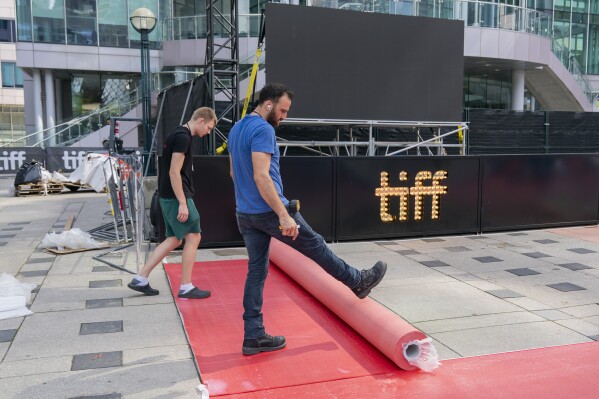 Workers roll out a red carpet ahead of the opening night of the 48th edition of the Toronto International Film Festival (TIFF) in Toronto, on Thursday, Sept. 7, 2023. The festival runs through Sept. 17. (Spencer Colby/The Canadian Press via AP)
