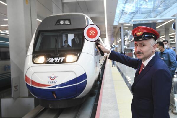 In this photo provided by Turkey's Transportation Ministry, Minister Adil Karaismailoglu poses for images as a train departs for Istanbul from Ankara's train station, Turkey, Thursday, May 28, 2020. Turkey has resumed limited intercity train operations after a two-month suspension as the country eases restrictions imposed to contain the coronavirus outbreak.(Transportation Ministry via AP )