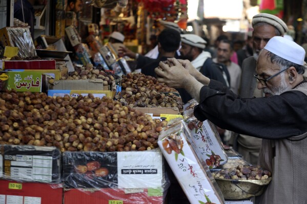 People buy dates in preparation for the upcoming Muslim fasting month of Ramadan, in Peshawar, Pakistan, Saturday, March 9, 2024. (AP Photo/Muhammad Sajjad)