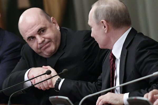 Russian President Vladimir Putin, right, and new Russian Prime Minister Mikhail Mishustin shake hands during a new cabinet meeting in Moscow, Russia, Tuesday, Jan. 21, 2020. Putin formed his new Cabinet Tuesday, replacing many of its members but keeping his foreign, defense and finance ministers in place. (Alexei Nikolsky, Sputnik, Kremlin Pool Photo via AP)