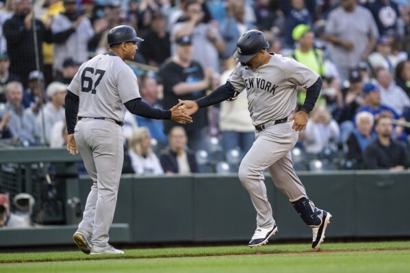 New York Yankees' Trent Grisham, right, is congratulated by third base coach Luis Rojas, left, after hitting a solo home run during the fourth inning of a baseball game against the Seattle Mariners, Monday, May 12, 2025, in Seattle. (AP Photo/Stephen Brashear)