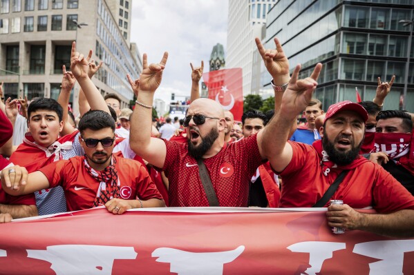 Turkey fans show the 'wolf salute', the origin of which is attributed to a right-wing extremist movement, during a fan walk before the start of the Euro 2024 quarterfinal soccer match between Netherlands and Turkey in Berlin, Saturday, July 6, 2024. (Christoph Soeder/dpa via AP)
