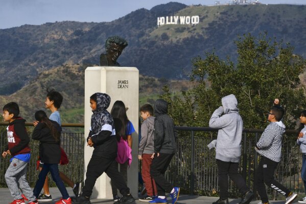 In this Friday, Jan. 17, 2020, photo, school children walk past a bust of actor James Dean during a field trip, at the Griffith Observatory in the Griffith Park area of Los Angeles. Travis Cloyd, who is leading the revival of Dean for his appearance in "Finding Jack," says his company will eventually offer the late actor's digital likeness for a range of roles in movies, TV and video games. (AP Photo/Richard Vogel)