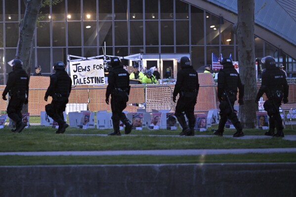 A line of police in riot gear walk past police dismantling pro-Palestinian encampment at MIT, before dawn Friday, May 10, 2024, in Cambridge, Mass. (AP Photo/Josh Reynolds)