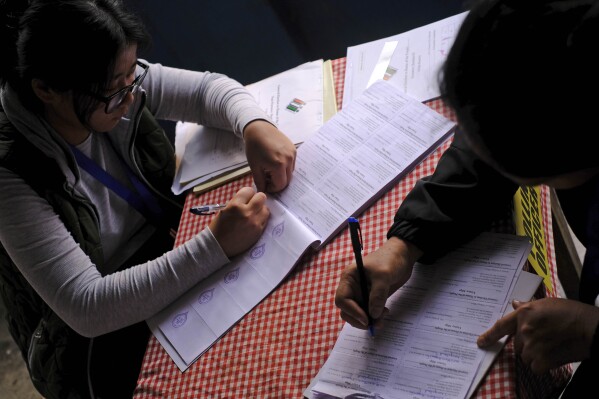 Polling officers Neichutuonuo Yhome, 27, left, and Nukutholu Nienu, 44, prepare election related paperwork on the eve of polling in Chedema village, in the northeastern Indian state of Nagaland, Thursday, April 18, 2024. (AP Photo/Yirmiyan Arthur)