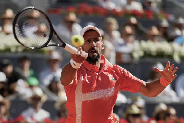 Novak Djokovic of Serbia returns the ball against Matteo Arnaldi of Italy during the Madrid Open tennis tournament in Madrid, Spain, Saturday, April 26, 2025. (AP Photo/Manu Fernandez)