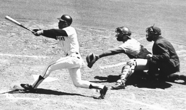 FILE - San Francisco Giants' Willie Mays watches the 3,000th hit of his career, a single to left, in the second inning against the Montreal Expos at Candlestick Park in San Francisco on July 18, 1970. Also watching are Expos catcher John Bateman and umpire Mel Steiner. Mays, the electrifying “Say Hey Kid” whose singular combination of talent, drive and exuberance made him one of baseball’s greatest and most beloved players, has died. He was 93. Mays' family and the San Francisco Giants jointly announced Tuesday night, June 18, 2024, he had “passed away peacefully” Tuesday afternoon surrounded by loved ones. (AP Photo/Robert H. Houston, File)