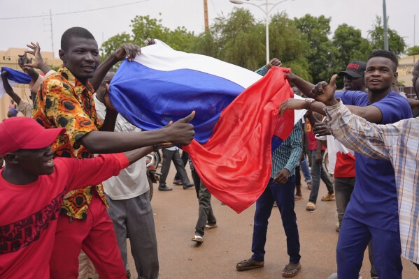 Supporters of mutinous soldiers hold a Russian flag as they demonstrate in Niamey, Niger, Thursday, July 27 2023. Governing bodies in Africa condemned what they characterized as a coup attempt Wednesday against Niger's President Mohamed Bazoum, after members of the presidential guard declared they had seized power in a coup over the West African country's deteriorating security situation. (AP Photo/Sam Mednick)