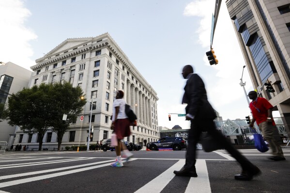 FILE - People cross the street near the Fulton County Courthouse, Aug. 14, 2023, in Atlanta. Court and other systems in Fulton County, Georgia's largest county is still repairing damage inflicted on its government offices by a cyberattack a month ago. Hackers in late January 2024 shut down online systems and phone service in Fulton County, which includes most of Atlanta.(AP Photo/Alex Slitz, File)