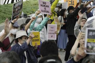 Protesters gather outside the parliament in which a revision to an immigration and refugee law was approved, in Tokyo, Friday, June 9, 2023. Japan’s parliament on Friday approved a controversial revision to an immigration and refugee law that would allow forced repatriation of asylum seekers whose refugee status is still in process, a measure the authorities say prevents long-term detention but rights activists criticize would increase risks of persecution. (Kyodo News via AP)