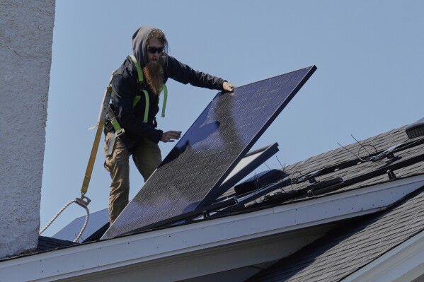Theodore Tanczuk, of solar installer YellowLite, puts a panel on a roof of a home in Lakewood, Ohio, Wednesday, April 16, 2025. (AP Photo/Sue Ogrocki)