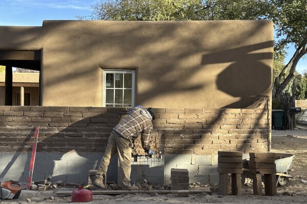 A mason works on an adobe-brick wall in on a residential lane lined with multimillion-dollar homes in Santa Fe, N.M., on Friday, Nov. 3, 2023. Voters are deciding whether to tax mansions to pay for affordable housing initiatives in a state capital city prized for its desert-mountain vistas, vibrant arts scene and stucco architecture rooted in Native American and Spanish-colonial tradition. (AP Photo/Morgan Lee)