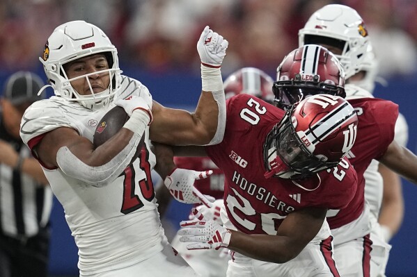 Louisville running back Isaac Guerendo (23) is tackled by Indiana defensive back Louis Moore (20) during the first half of an NCAA college football game, Saturday, Sept. 16, 2023, in Indianapolis. (AP Photo/Darron Cummings)