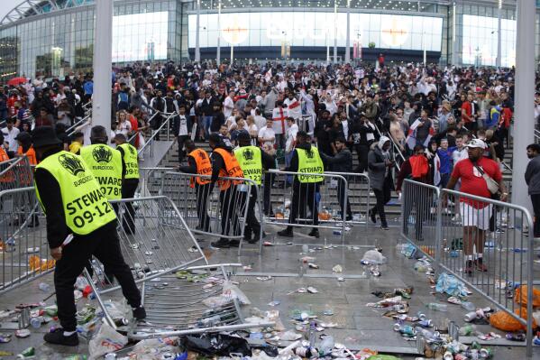 FILE - Stewards replace barricades after they were knocked over by supporters outside Wembley Stadium in London, during the Euro 2020 soccer championship final match between England and Italy, on  July 11, 2021. An investigation into the disorder at the European Championship final says aggression by England fans exposed an “embarrassing” part of the national culture that endangered lives and should lead to entry to stadiums being prohibited to anyone chanting abuse and high on drugs or drunk. (AP Photo/David Cliff, File)