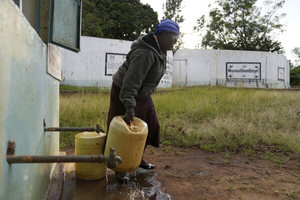 Joyce Mule fills jugs with water from a rock catchment system in Makueni County, Kenya on Thursday, Feb. 29, 2024. (AP Photo/Brian Inganga)