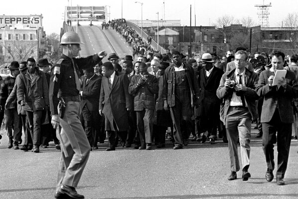 
              FILE - In this March 10, 1965 file photo, demonstrators, including Dr. Martin Luther King, Jr., stream over an Alabama River bridge at the city limits of Selma, Ala., during a voter rights march. King's participation in the 54-mile (87-kilometer) march from Selma, Ala., to the state capital of Montgomery elevated awareness about the troubles blacks faced in registering to vote. (AP Photo/File)
            
