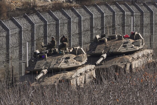 Israeli soldiers sit on top of a tank along the so-called Alpha Line that separates the Israeli-annexed Golan Heights from Syria, in the town of Majdal Shams, Monday, Dec. 9, 2024. (AP Photo/Matias Delacroix)