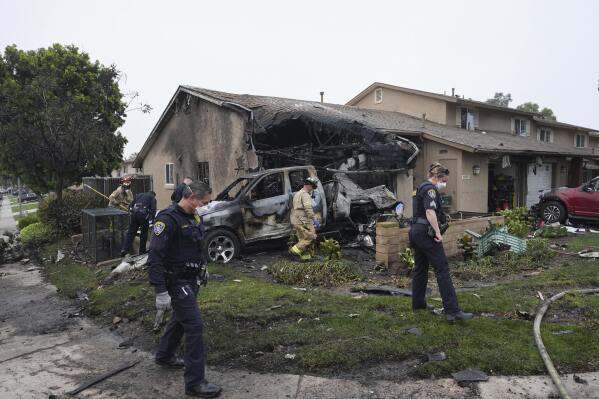 Authorities work the scene where a small plane crashed into a San Diego neighborhood, setting several homes on fire and forcing evacuations along several blocks early Thursday, May 22, 2025. (AP Photo/Gregory Bull)