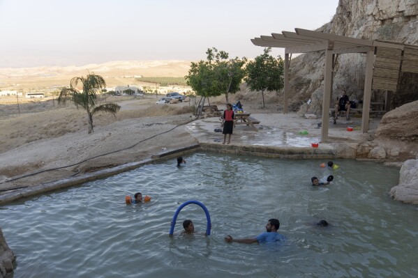 Israeli children swim in a pool at the Jewish settlement of Mevo'ot Yericho, in the Jordan Valley near the Palestinian city of Jericho, Friday, Aug. 11, 2023. In the occupied West Bank, where Israeli water pipes don’t reach, Palestinians say they can't get enough water to irrigate their farms. By comparison, the neighboring Jewish settlements look like an oasis with swimming pools. (AP Photo/Ohad Zwigenberg)