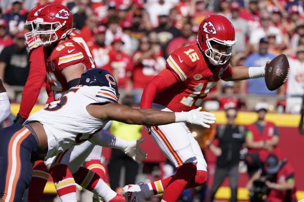 Kansas City Chiefs quarterback Patrick Mahomes, right, slips past Chicago Bears defensive end DeMarcus Walker during the first half of an NFL football game Sunday, Sept. 24, 2023, in Kansas City, Mo. (AP Photo/Ed Zurga)