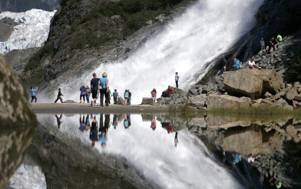 FILE - In this July 31, 2013, file photo, tourists visiting the Mendenhall Glacier in the Tongass National Forest are reflected in a pool of water as they make their way to Nugget Falls in Juneau, Alaska. The U.S. Forest Service announced plans Wednesday, Oct. 28, 2020, to lift restrictions on road building and logging in Tongass National Forest, a largely pristine rainforest in southeast Alaska that provides habitat for wolves, bears and salmon. Conservation groups vowed to fight the decision. (AP Photo/Charles Rex Arbogast, File)