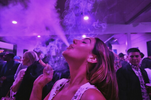 FILE - A guest takes a puff from a marijuana cigarette at the Sensi Magazine party celebrating the 420 holiday in the Bel Air section of Los Angeles, April 20, 2019. Marijuana advocates are gearing up for Saturday, April 20, 2024. Known as 4/20, marijuana's high holiday is marked by large crowds gathering in parks, at festivals and on college campuses to smoke together. This year, activists can reflect on how far the movement has come. (AP Photo/Richard Vogel, File)