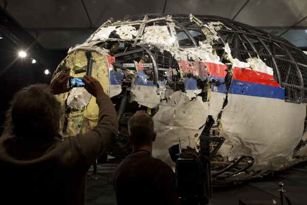 FILE - Journalists take images of part of the reconstructed forward section of the fuselage after the presentation of the Dutch Safety Board's final report into what caused Malaysia Airlines Flight 17 to break up high over Eastern Ukraine, during a press conference in Gilze-Rijen, Netherlands, Tuesday, Oct. 13, 2015 The Dutch government has spent more than 166 million euros ($180 million) dealing with the aftermath of the downing of Malaysia Airlines flight MH17 over eastern Ukraine in 2014 — from repatriating victims' bodies to investigating and prosecuting some of those involved in the downing, according to an official report Thursday, Feb. 29, 2024. (AP Photo/Peter Dejong, File)