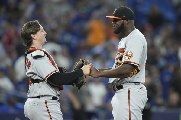 Baltimore Orioles catcher Adley Rutschman, left, and relief pitcher Felix Bautista, right, celebrate after defeating the Toronto Blue Jays in baseball game action in Toronto, Monday, July 31, 2023. (Nathan Denette/The Canadian Press via AP)