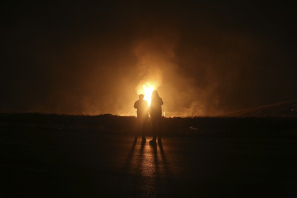 Two men look at flames after a natural gas pipeline explodes outside the city of Boroujen in the western Chaharmahal and Bakhtiari province, Iran, in early Wednesday, Feb. 14, 2024. Explosions struck a natural gas pipeline in Iran early Wednesday, with an official blaming the blasts on a "sabotage and terrorist action" in the country as tensions remain high in the Middle East amid Israel's war on Hamas in the Gaza Strip. (Reza Kamali Dehkordi/Fars News Agency via AP)