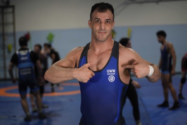 Iranian wrestler Iman Mahdavi, 28, a member of the Refugee Team for the Paris Olympics, poses at the Lotta Club Seggiano gym, in Pioltello, near Milan, Italy, Wednesday, Feb. 28, 2024. The Refugee Team for the Paris Olympics will feature 36 athletes from 11 countries in 12 sports. International Olympic Committee president Thomas Bach says the team was selected from more than 70 scholarships. Instead of competing under the Olympic flag, the refugees will have their own emblem featuring a heart at its center surrounded by arrows. (AP Photo/Luca Bruno)