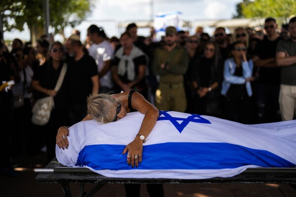 Antonio Macías' mother cries over her son's body covered with the Israeli flag at Pardes Haim cemetery in Kfar Saba, near Tel Aviv, Israel, Sunday, Oct. 15, 2023. Macias was killed by Hamas militants while attending a music festival in southern Israel earlier this month. (AP Photo/Francisco Seco)